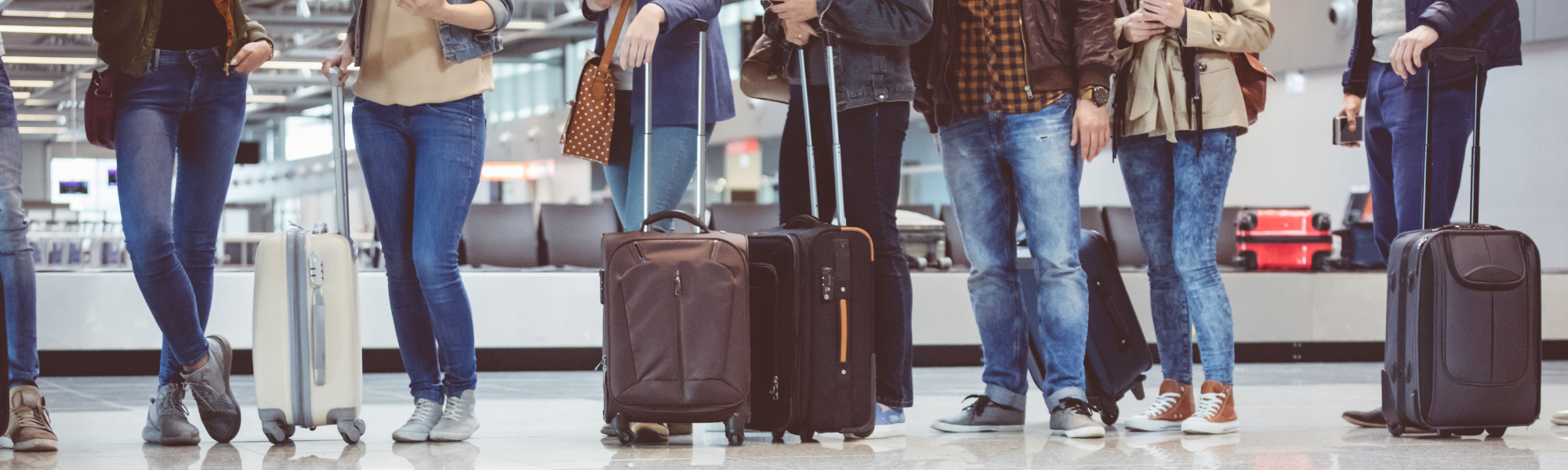 Eine Gruppe Menschen wartet am Gepäckband am Flughafen